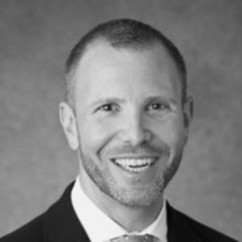 Headshot of Ron Ellis DO, MBA a man with short hair in a suit jacket smiling.